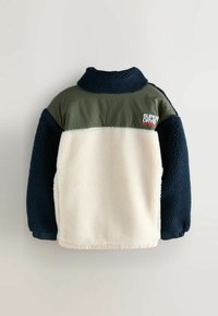 Fleece bunda s námořnickými rukávy a límcem, krémovým tělem, olivově zeleným sedlem a logem "Superdry" na pravé straně horní části zad.