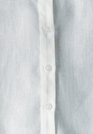 Witte linnen blouse met een verticale rij van vijf witte plastic knopen en een zachte, gestructureerde stof, die een ademende, lichte uitstraling benadrukt.