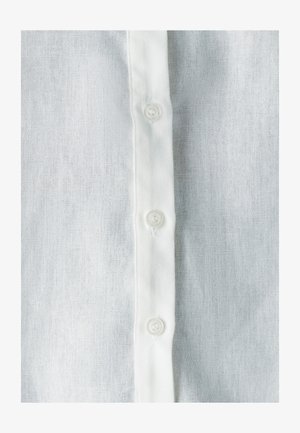 White linen shirt with a vertical row of five white plastic buttons and a soft, textured fabric, emphasizing a breathable, light appearance.