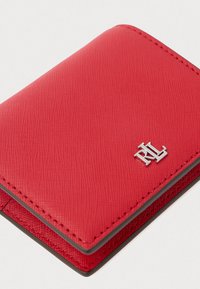 Rote Lederbörse mit strukturierten Oberflächen und silbernem Logo, verfügt über ein kompaktes Design und kontrastierende Nähte entlang der Kanten.