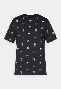 T-shirt en coton noir avec un motif répété de logos Nike blancs et violets et le texte "JUST DO IT." Encolure ronde et manches courtes.