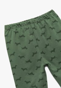 Leggings de algodón verde con una cintura elástica, que cuentan con un patrón repetido de dachshund en un tono verde más oscuro. Textura suave y diseño ajustado.