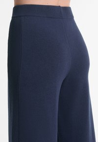 Dunkelblaue Strickhose mit geripptem Bund und strukturierter Stoffqualität, entworfen mit geradem Schnitt und minimalen Nahtdetails.