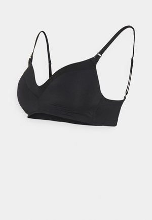 Black wireless bra with adjustable straps, seamless design, smooth texture, and modest coverage. Features a wide band for support.