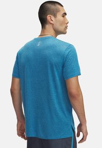 Camiseta deportiva azul hecha de tela texturizada. Presenta un cuello redondo, mangas cortas y un dobladillo dividido para facilitar el movimiento.