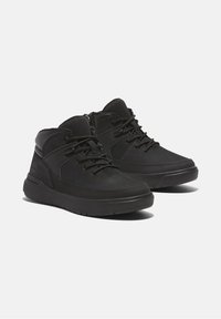 Czarne półbuty na kostkę wykonane z skóry i materiałów syntetycznych. Posiadają sznurowany design, teksturowane akcenty oraz wkładkę amortyzującą.