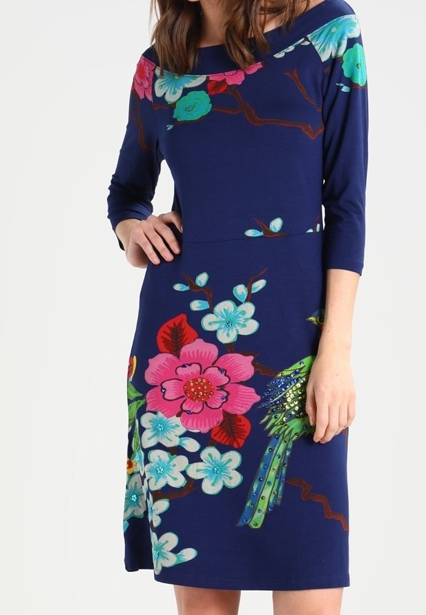 Marinblå klänning med trekvartslånga ärmar, med stora blommönster i rosa, grönt och ljusblått, med en fågeldekoration.