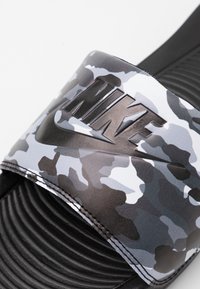 Svart og grå kamuflasje slide sandal med en teksturert stropp med preget logo. Rillede såler for bedre grep og komfort.