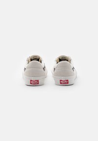 Paar weiße und graue Vans-Sneaker von hinten gezeigt, mit sichtbaren roten "Off The Wall"-Logos an den Fersen vor einem weißen Hintergrund.