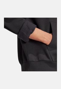 Felpa nera con polsini arrotolati, dotata di tasca laterale e di un tessuto morbido e strutturato. Design semplice con una vestibilità comoda.