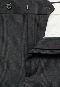 Crne karirane hlače s glatkom teksturom, s dugmetom za zatvaranje, patentnim zatvaračem i kontrastnim bijelim oblogom unutra.