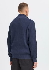 Pull en maille bleu marine avec un motif texturé, col montant et poignets et ourlet côtelés. Fabriqué en fil doux et épais.