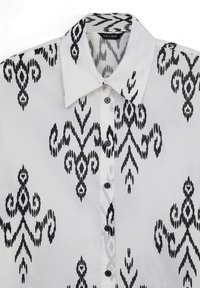 Camicia bianca con bottoni, caratterizzata da un motivo ikat nero, colletto strutturato e sei bottoni neri lungo la patta anteriore.