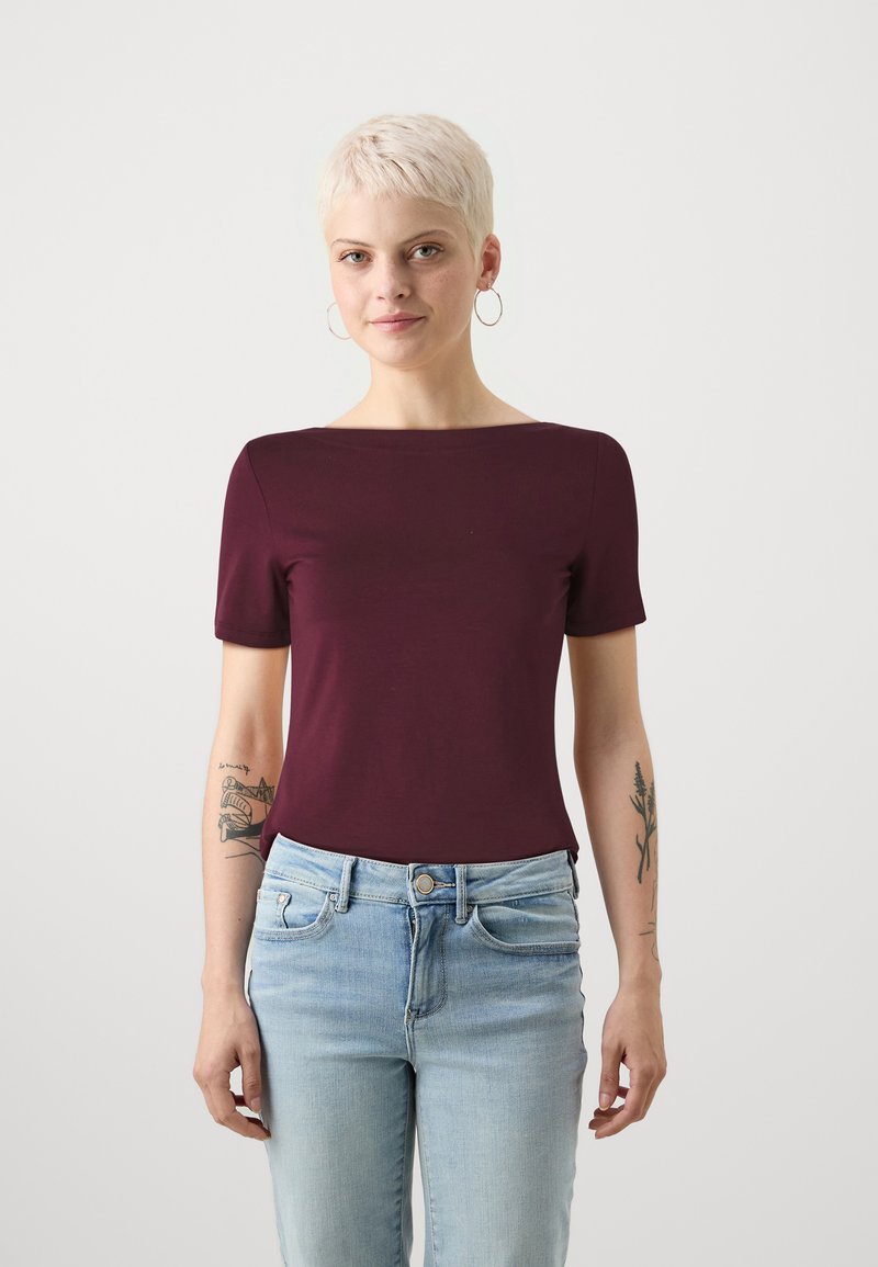 Burgunderfarget t-skjorte med korte ermer og båthals, laget av mykt stoff. Brukt sammen med lyseblå denimjeans. Enkelt design uten mønster.