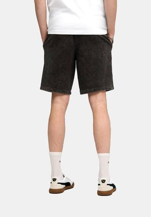 Dunkelgraue Jeansshorts mit verwaschener Textur, Seitentaschen und sichtbaren Nähten. Getragen mit weißen Socken und Sneakers mit schwarzen Akzenten.