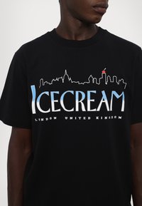Black cotton t-shirt featuring a skyline graphic and the text "ICECREAM LONDON UNITED KINGDOM" in white and blue.