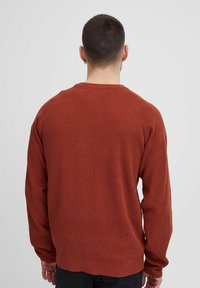 Maglione a maniche lunghe color ruggine con texture a coste, scollo a girocollo e vestibilità rilassata. La parte posteriore presenta cuciture a coste sulle spalle e sull'orlo.