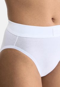 Witte katoenen slips met een gladde tailleband, platte naden en delicate golvende randen, die een naadloos ontwerp tonen voor optimaal comfort.
