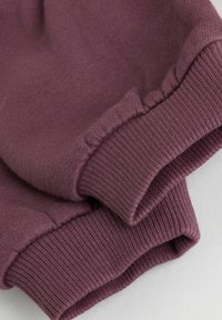 Lilla sweatshirt-stof med ribbede manchetter i en glat tekstur. Manchetterne er elastiske og pænt syet med en ren afslutning.