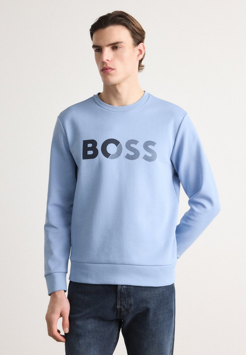 Light blue sweatshirt made of soft material, featuring a bold black "BOSS" logo in varying textures, with ribbed cuffs and hem.