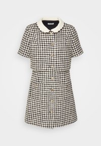 Robe à manches courtes noire et blanche à motif pied-de-poule, avec des boutons dorés sur le devant et un col crème festonné.