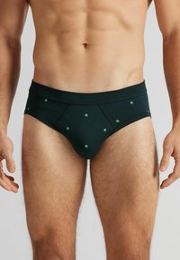 Pánské slipy v tmavě zelené barvě z bavlny, se vzorem malých zelených geometrických tvarů. Elastický pas, přiléhavý střih a hladká textura.