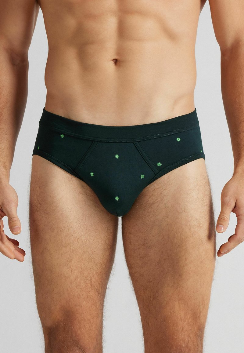 Pánské slipy v tmavě zelené barvě z bavlny, se vzorem malých zelených geometrických tvarů. Elastický pas, přiléhavý střih a hladká textura.