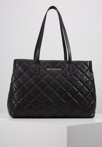 Bolso tote de cuero negro acolchado con dos asas resistentes y un logo dorado "VALENTINO" en la parte frontal, con forma rectangular y textura suave.