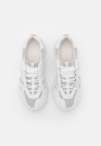 Paire de baskets blanches avec des panneaux en mesh et des lacets, vues de dessus sur fond blanc.
