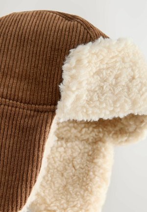 Chapeau en velours côtelé marron avec une doublure en fausse fourrure crème et des rabats d'oreilles, présentant une texture en côtes verticales et des accents doux et pelucheux.
