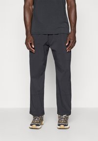 Black, lightweight, loose-fitting cargo pants with multiple seams and pockets, paired with dark, textured sneakers.