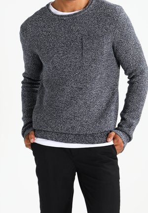 Gray knit sweater with a round neckline, textured fabric, and a small chest pocket. Paired with black trousers.