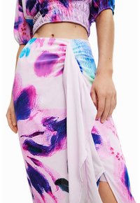 Barevná, vzorovaná sukýnka v odstínech růžové, fialové a modré, vyrobená z lehkého materiálu s drapériemi a bočním rozparkem.