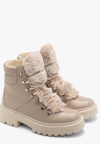 Beżowe skórzane botki z sztucznym futrem, okrągłym noskiem i grubą gumową podeszwą. Posiadają metalowe oczka i sznurowadła wykończone miękkimi beżowymi akcentami.