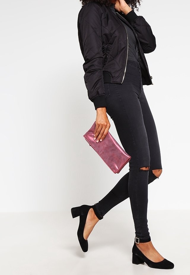 Kvádrkovaná černá bomber bunda, přiléhavé černé džínsy s roztrženými detaily, černé semišové boty na blokovém podpatku a růžová metalická psaníčko.