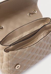 Beige quilted handbag with gold hardware. Features an interior with two compartments and a button closure. Smooth, textured material.