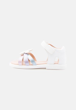 Witte sandalen met drie iriserende bandjes in roze, lavendel en blauw. Klittenband sluiting en een gladde zool. Geen extra versieringen.