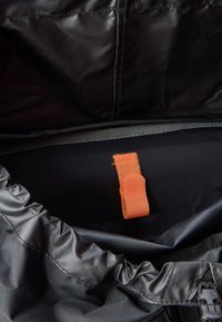 Must mustkott, mille sisemuses on sile tekstuur; sellel on silmatorkav oranž kangas silt ja kogutud äär avamisel.