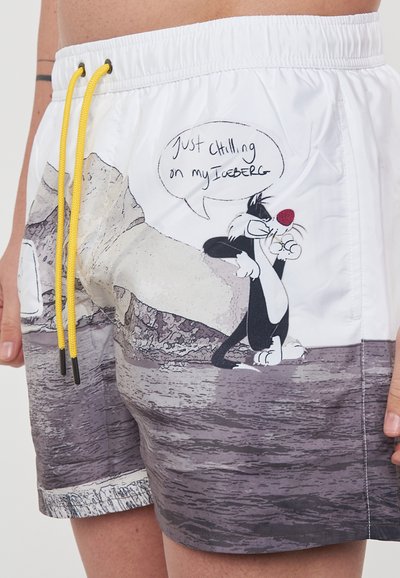Costume da bagno da uomo in bianco e grigio. Presenta un personaggio dei cartoni animati su un ghiaccio con una nuvoletta di dialogo. Vita elasticizzata con cordino giallo.