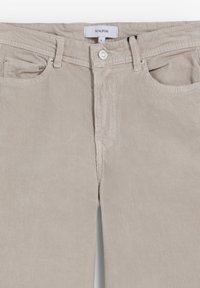 Beżowe spodnie kordowe o prostym kroju, z dwoma przednimi kieszeniami, guzikiem zapięciem i subtelną teksturą prążkowaną. Widoczna metka marki na pasku.