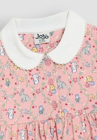Robe en tissu rose avec un col blanc, des motifs floraux et de lapins, avec des boutons et une jupe froncée. Taille 18-24 mois.