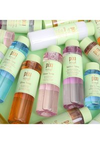 Variasjon av Pixi hudpleietonika i sylinderformede flasker; fargene inkluderer rosa, oransje, blå og hvit; merket med grønne hetter og aksenter.