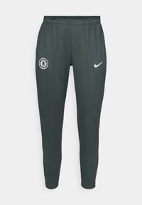 Mørkegrå treningbukser med elastisk midje, med Chelsea fotballklubb-logo på venstre side og en hvit Nike swoosh på høyre side.