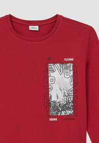 Rode langekous t-shirt van katoen. Heeft een grafische print met de tekst "TECHNO" en "SOUND" in contrasterende kleuren.
