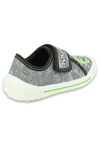 Baskets en tissu gris avec des accents verts, semelle blanche et strap à boucle. Caractéristiques : surface texturée et détails graphiques ludiques.