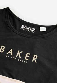Sort bomulds t-shirt med rund halsudskæring, der har "BAKER by TED BAKER" trykt i guld på forsiden. Etiketten angiver "MADE IN BANGLADESH."