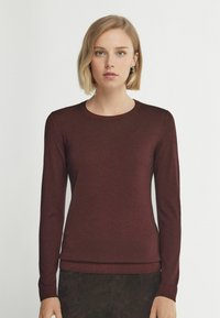 Burgunderfärgad långärmad tröja med rund halsringning, tillverkad av mjukt tyg; figursydd design med ribbat avslut och mudd.