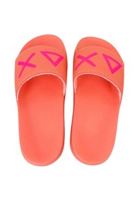 Een paar koraalkleurige slide-sandalen met felroze PlayStation-controller symbolen op de banden, geïsoleerd op een witte achtergrond.