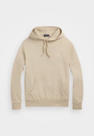 Bež hoodie izrađen od mekog materijala, s prednjim džepom, vezicama i malim logotipom na prsima. Rukavi i donji rub su rebrasti.