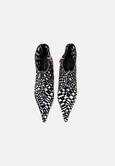 Paire de bottines à carreaux noir et blanc à bout pointu avec fermetures éclair latérales, vues de dessus sur un fond blanc uni.